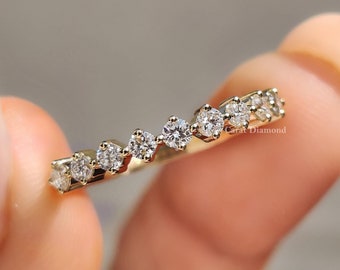 May include: A gold band ring with a row of small, round diamonds set in a staggered pattern. The ring is on a finger.