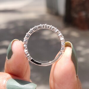 K&ouml;nnte beinhalten: Ein silberner Ring mit einer Reihe kleiner, runder Diamanten, die in Pav&eacute;-Fassung gefasst sind. Der Ring wird an einem Finger gezeigt.