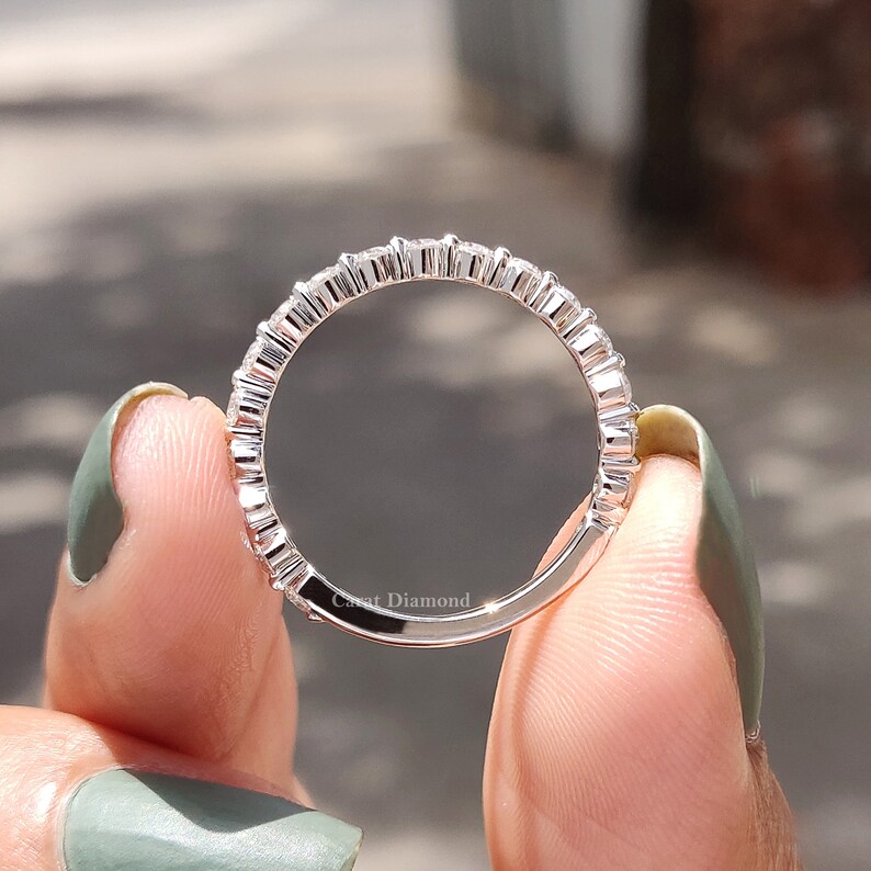 K&ouml;nnte beinhalten: Ein silberner Ring mit einer Reihe kleiner, runder Diamanten, die in Pav&eacute;-Fassung gefasst sind. Der Ring wird an einem Finger gezeigt.