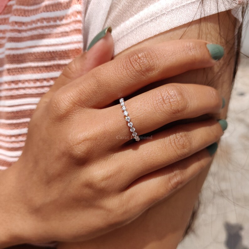 K&ouml;nnte beinhalten: Ein zarter Ewigkeitsring mit einer Reihe kleiner, runder, klarer Diamanten, die in eine silberne Band gefasst sind.