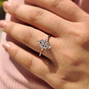 Marquise diamond ring crafted with pear side accents and a tapered shank.