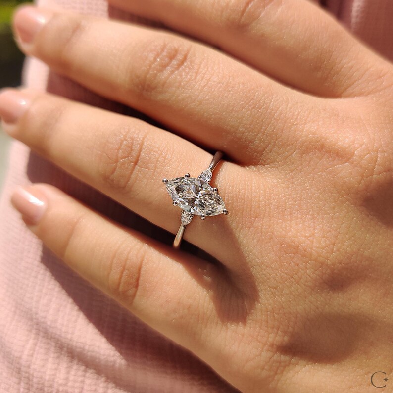 Marquise diamond ring crafted with pear side accents and a tapered shank.