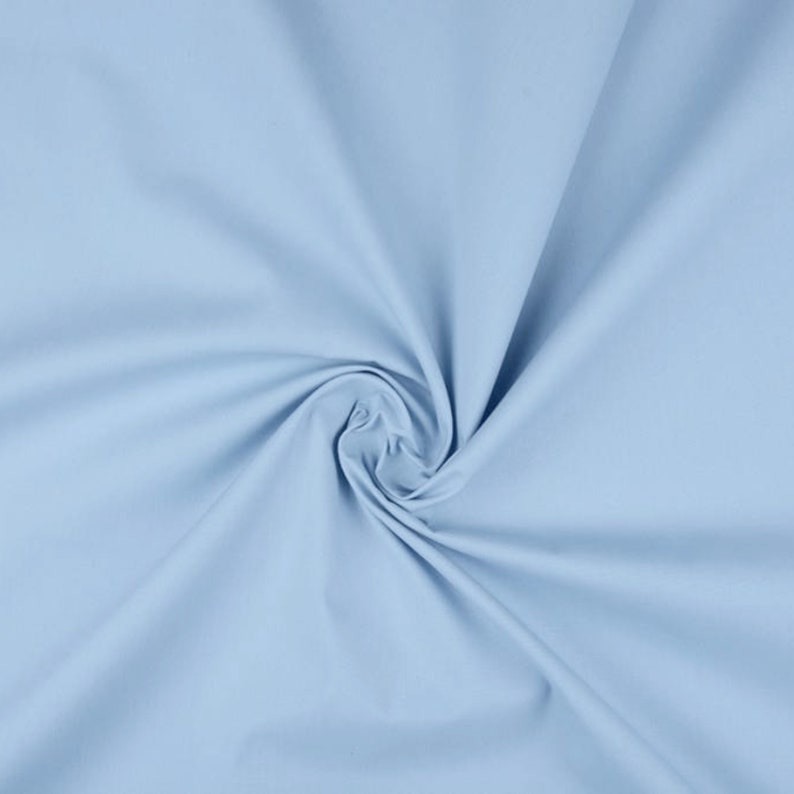 May include: A light blue fabric swatch with a smooth, soft texture. The fabric is folded and draped, showcasing its drape and flow.