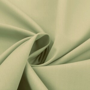 May include: A smooth, light green fabric with a soft, flowing texture. The fabric is folded and draped, creating a sense of movement and fluidity.