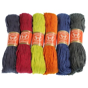 May include: Six spools of embroidery floss in various colors, including gray, red, green, orange, blue, and dark gray. Each spool has a label with the text "Butterfly Super 10 Merecerized Cotton Petaloudas".
