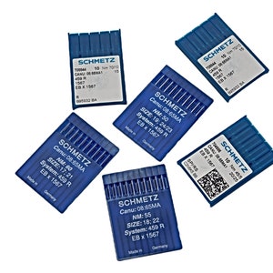 Puede incluir: Cinco paquetes azules de agujas para máquina de coser, cada uno con la marca "SCHMETZ" y detalles sobre el tamaño de la aguja, el sistema y el número de canu. Los paquetes están dispersos sobre un fondo blanco.