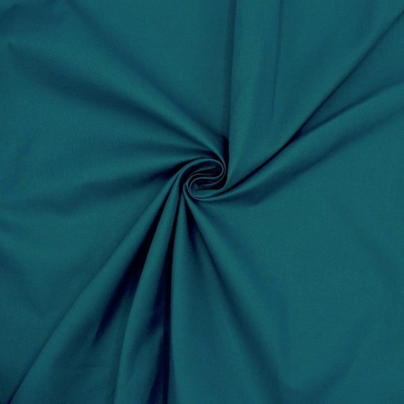 May include: A close-up of a teal fabric with a smooth texture. The fabric is folded and draped, creating soft folds and curves.