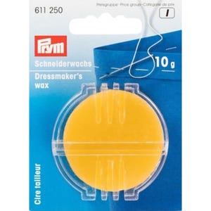 May include: A round yellow sewing wax in a clear plastic container. The container has a label that says "Schneiderwachs Dressmaker's wax" and "Cire tailleur".