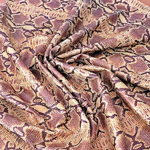 Peut inclure: Gros plan sur un tissu à motif peau de serpent. Le tissu présente un mélange de couleurs marron, beige et noir. La matière est drapée, révélant la texture et le motif du design peau de serpent. Le tissu est probablement utilisé pour des vêtements ou des accessoires.