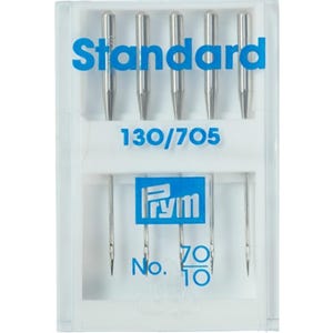 Op de afbeelding: Een verpakking met vier zilveren naalden voor een naaimachine in een doorzichtige plastic doos. De doos heeft een blauw etiket met de tekst "Standard 130/705 Prym No. 70/10".