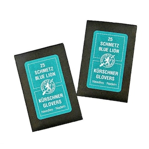 May include: Two black packets of sewing needles with teal labels. Each label reads "25 SCHMETZ BLUE LION" and "KÜRSCHNER GLOVERS Needles Nadeln". A logo of a lion holding a needle is also on the label.