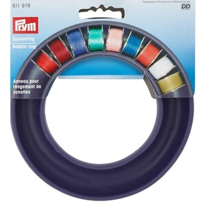 May include: Purple bobbin ring for storing spools of thread. The ring has 12 slots for spools and is labelled "Spulenring Bobbin ring".