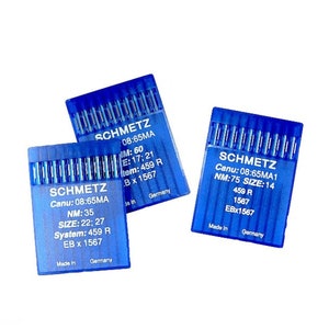May include: Three blue plastic packages of sewing machine needles. Each package has the brand name "SCHMETZ" printed on it, along with the needle size and other information.