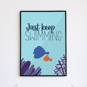May include: A framed art print with the words "Just keep SWIMMING" in dark blue lettering on a light blue background. The print features illustrations of a blue fish, an orange fish, and purple coral.