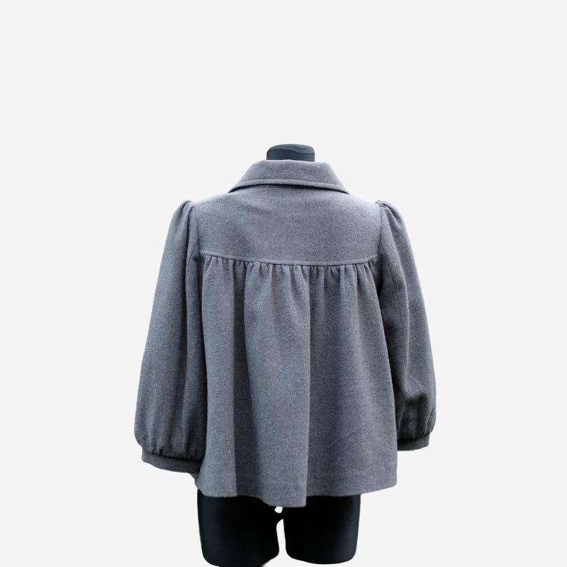 A gray wool coat with puffed sleeves and a ruffled collar is displayed on a mannequin.