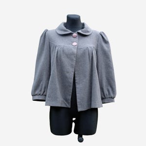 A gray coat with puffed sleeves and buttons is displayed on a mannequin.