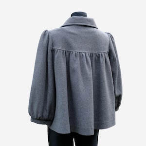 A gray wool coat with puffed sleeves and a ruffled collar is displayed on a mannequin.