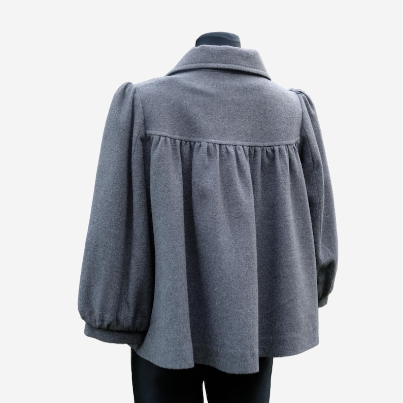 A gray wool coat with puffed sleeves and a ruffled collar is displayed on a mannequin.