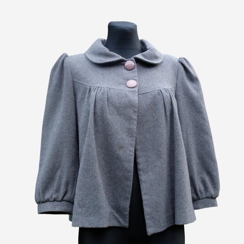 A gray wool coat with puffed sleeves and buttons, displayed on a mannequin.