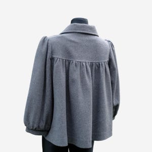 A gray wool coat with puffed sleeves and a high collar is displayed on a mannequin.