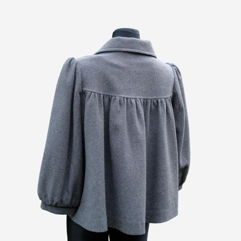 A gray wool coat with puffed sleeves and a high collar is displayed on a mannequin.