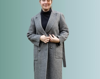 May include: A gray double-breasted wool coat with a belt. The coat has two pockets on the front and a button closure.