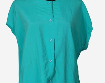May include: A teal-colored short-sleeved blouse with a button-up front. The blouse has a round neckline and is displayed on a black mannequin. The fabric appears to be lightweight and slightly textured, with a relaxed fit.