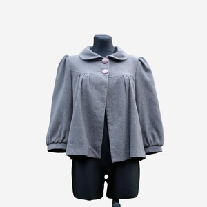 A gray coat with puffed sleeves and buttons is displayed on a mannequin.