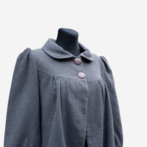 A gray wool coat with puffed sleeves and buttons, displayed on a mannequin.