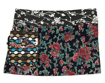 May include: A black and white floral patterned skirt with a black and white polka dot and turquoise patterned pocket. The skirt has a black and white patterned waistband with silver accents.