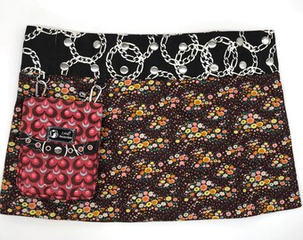 Puede incluir: Una falda de estampado de cadena en blanco y negro con estampado floral y un bolsillo rojo y blanco con el texto "Zana Amsterdam" en él.