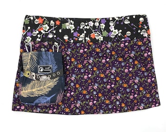 May include: A purple and black floral skirt with a small black pocket with a feather design and the text "Zane Accessories" on it.