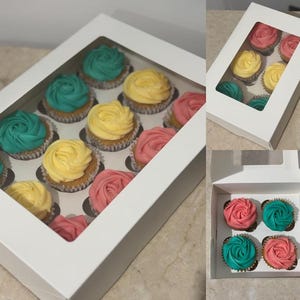 May include: A white box containing cupcakes with teal, yellow, and pink frosting. The cupcakes are arranged in rows. The box has a clear window on top. The cupcakes are in paper cases.