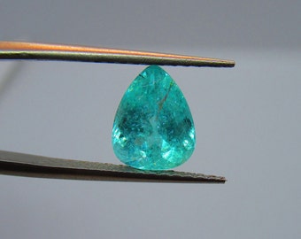 May include: A pear-shaped teal gemstone with inclusions, held by tweezers.