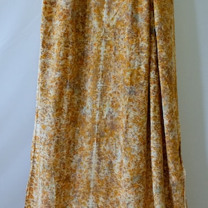 Puede incluir: Una cortina larga y fluida con un patrón abstracto de color óxido y blanco. La tela tiene una textura suave y fluida.