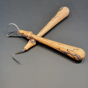 May include: Two dental tools with wooden handles. One tool has a curved, metal end, and the other has a rounded, metal end. The handles are light brown with dark brown and purple veining.