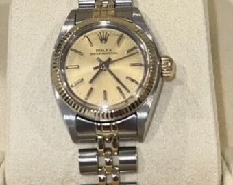 May include: A two-tone stainless steel and gold Rolex Oyster Perpetual wristwatch with a white dial and black Roman numeral hour markers. The watch has a date window at the 3 o'clock position and a fluted bezel.