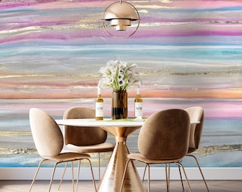 May include: A modern dining room set with a white round table, four tan upholstered chairs, and a gold-toned base. The background features a colorful abstract mural with gold accents. A gold pendant light hangs above the table.