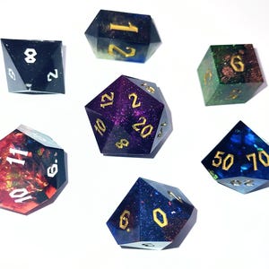May include: A collection of seven multi-sided dice in a variety of colours, including black, blue, green, and red, with gold numerals. The dice are made of a translucent material, with glitter and other decorative elements inside. Ideal for tabletop games.