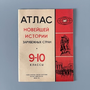 Puede incluir: Un libro de texto ruso antiguo, titulado "ATЛAC НОВЕЙШЕЙ ИСТОРИИ ЗАРУБЕЖНЫХ СТРАН". La portada roja y crema presenta ilustraciones de un globo, una estatua y una multitud. El texto indica que es para los grados 9-10, publicado en Moscú en 1984.