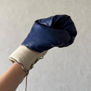 May include: A blue and white boxing glove with laces. The glove is made of leather and has a padded interior.
