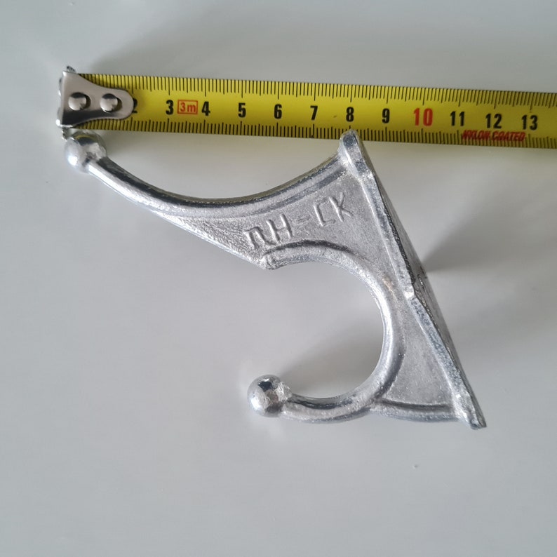May include: A silver metal hook with a rounded top and a curved hook. The hook has the letters "RH-CK" embossed on the back.
