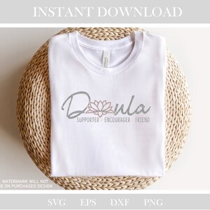 May include: White t-shirt with a gray and pink design that says "Dula" with a lotus flower and the words "Supporter, Encourager, Friend".