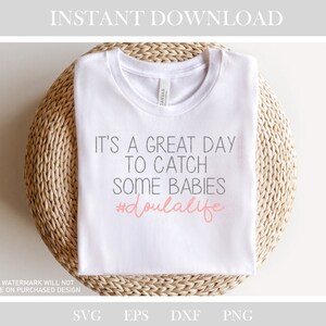 May include: White t-shirt with the text "It's a great day to catch some babies #doulalife" in black and pink lettering.