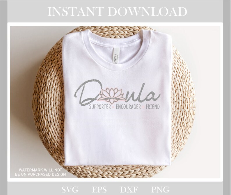 May include: White t-shirt with the word "Doula" in a script font, accompanied by a lotus flower graphic. Below the word are the words "Supporter, Encourager, Friend". The shirt is folded on a woven surface.
