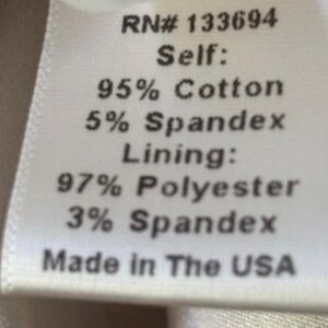 May include: A white fabric label with black text detailing the material composition. The label states "RN# 133694", "Self: 95% Cotton, 5% Spandex", "Lining: 97% Polyester, 3% Spandex", and "Made in The USA".