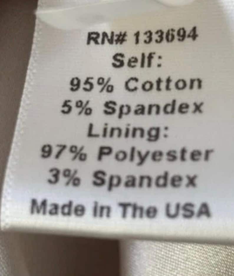 May include: A white fabric label with black text detailing the material composition. The label states "RN# 133694", "Self: 95% Cotton, 5% Spandex", "Lining: 97% Polyester, 3% Spandex", and "Made in The USA".