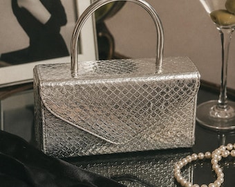 Bolso de noche vintage Delli de piel de serpiente plateada con estructura y asa superior. Bolso de estilo mod.