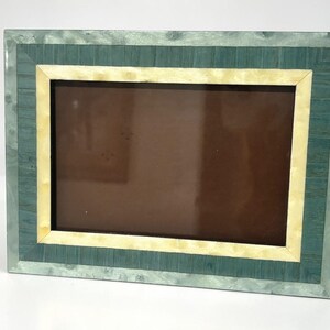 May include: Rectangular picture frame with a teal and cream color scheme. The frame has a teal outer border, a cream-colored inner border, and a brown interior. The frame is designed to hold a photograph or artwork.
