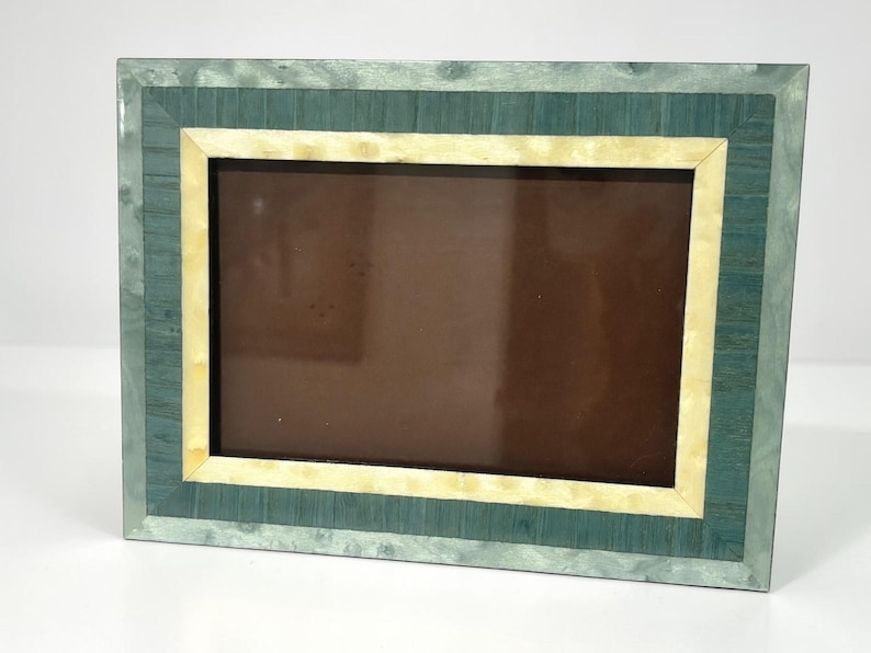 May include: Rectangular picture frame with a teal and cream color scheme. The frame has a teal outer border, a cream-colored inner border, and a brown interior. The frame is designed to hold a photograph or artwork.